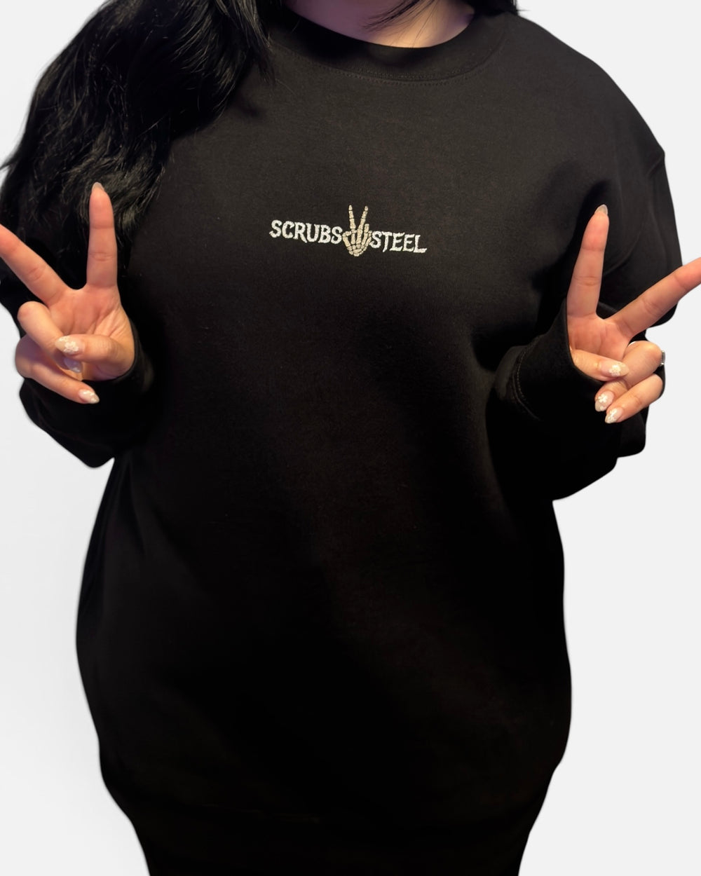 Front of the It's Giving Sepsis crewneck worn, small Scrubs and Steel chest wordmark with skeleton peace sign