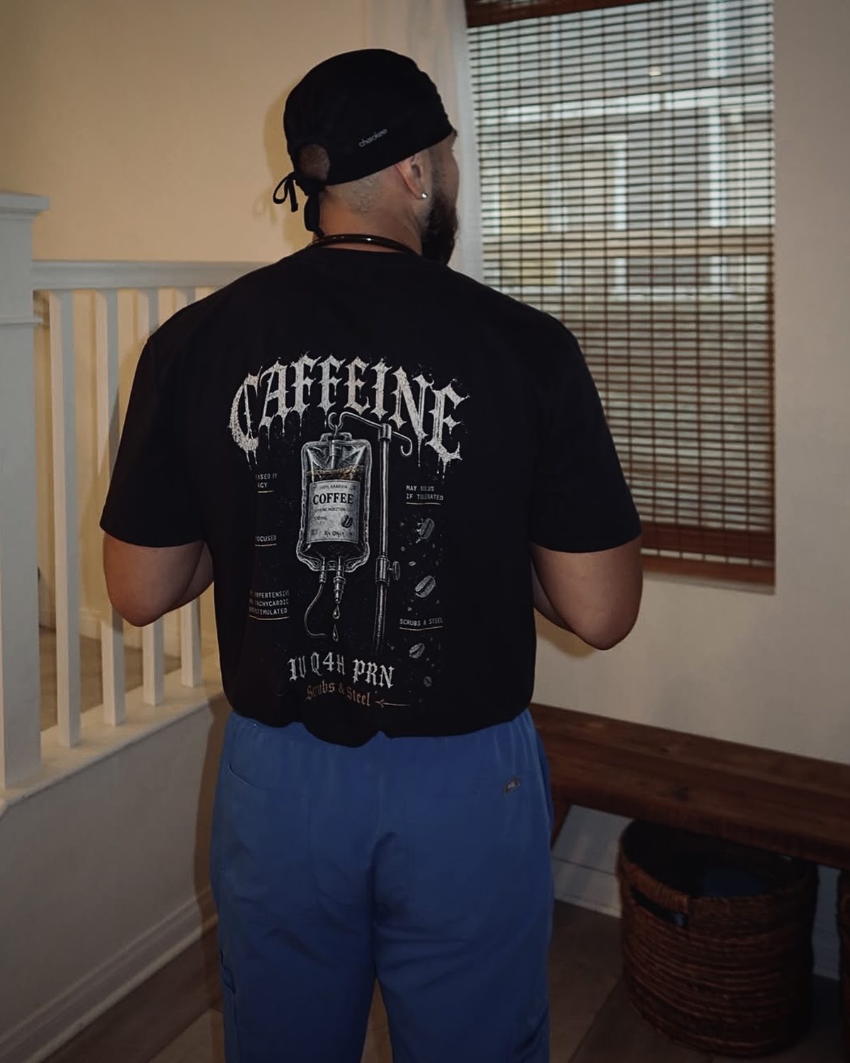 Back print of the Coffee IV tee worn with a scrub cap and blue scrubs