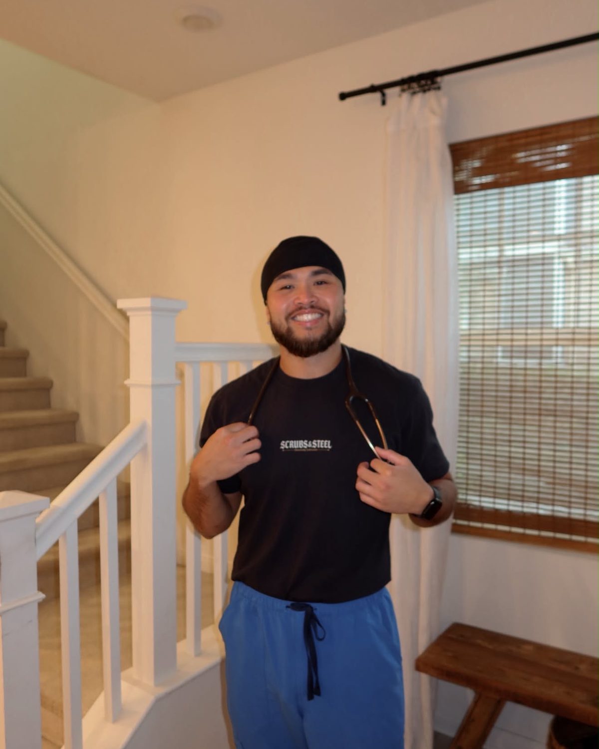 Nurse holding a stethoscope wearing the Scrubs & Steel front-logo tee